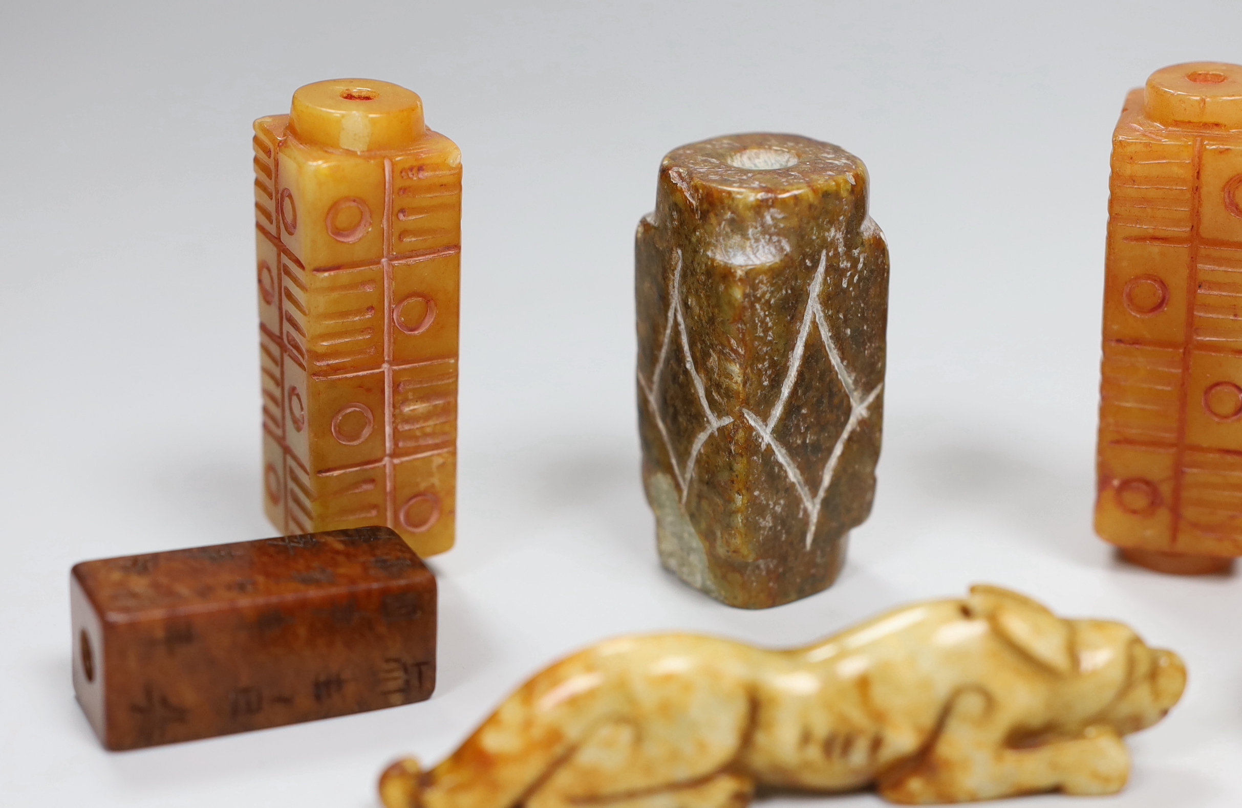 Eight Chinese archaistic jade or hardstone pendants/beads with carved decoration, the largest 9cm wide